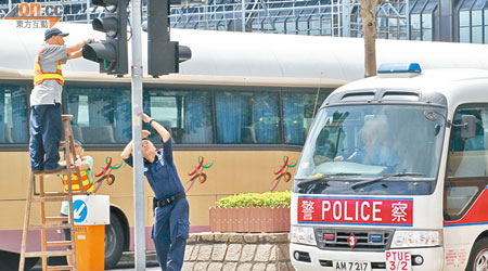 警方昨仔細檢查會展及君悅酒店四周的交通燈，似為加裝監察儀器作準備。（霍振鋒攝）