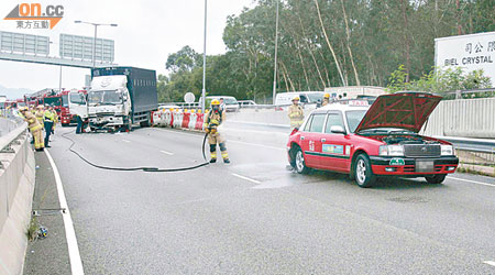 消防向的士車尾的石油氣缸射水降溫，以防爆炸。（趙瑞麟攝）