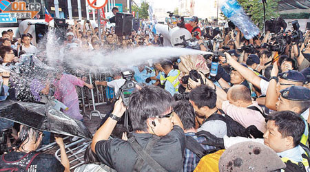 衝擊示威區的群眾向警員投擲水樽，警員向衝擊者施放胡椒噴霧。（伍鎮業攝）