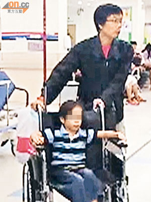 墮樓受輕傷男童，由父推着輪椅送入急症室治理。 （文健雄攝）