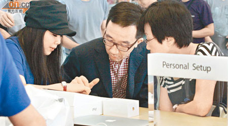 梁卓偉（中）與同行女士（右）專心聽售貨員（左）介紹iPad運作。（陳嘉順攝）
