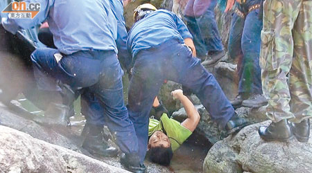 身穿T恤及泳褲的死者由搜救人員抬上水潭。（李子強攝）