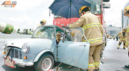 消防員搶救被困乘客，並為傷者打傘擋陽光。（曾志恆攝）