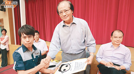 區議員鄺俊宇將示威物品交給吳克儉（中），要求對方取消國民教育課程。