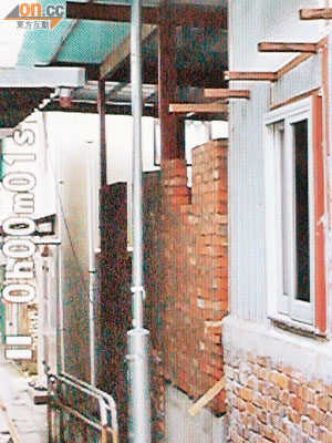 張先生村屋被非法興建的村屋（紅磚部分）堵塞，鐵皮貫穿燈柱。