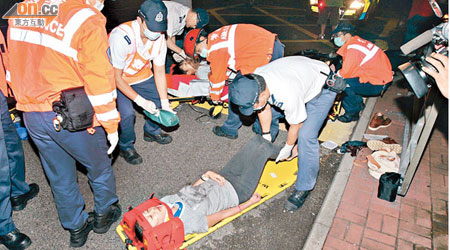 鐵騎男女受傷倒臥路面，救護員為其急救。（楊偉嶽攝）