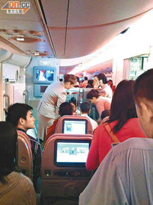 阿聯酋機艙服務員本周二在故障航機上為一名暈倒的空姐進行急救。（乘客提供）