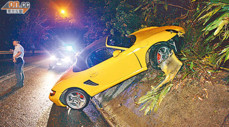 陳嘉信駕駛的跑車衝上護土牆，前輪沙板鬆脫。（呂浩鋒攝）