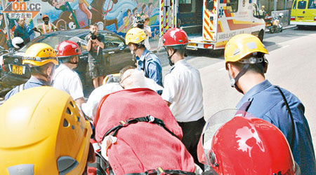 多名救援人員合力將疑心臟病發工人由地盤十六樓抬下送院。（馬竟峯攝）