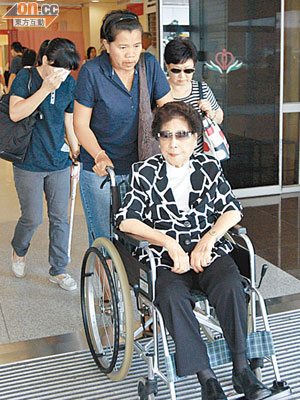 坐輪椅的死者母親一臉悲傷。