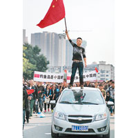 內蒙<br>呼和浩特一名示威者站在車頂揮舞國旗示威。（中新社圖片）