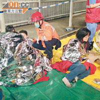 受輕傷者在碼頭由救護員檢查傷勢，並用錫紙包着身體保暖。（李豪杰攝）