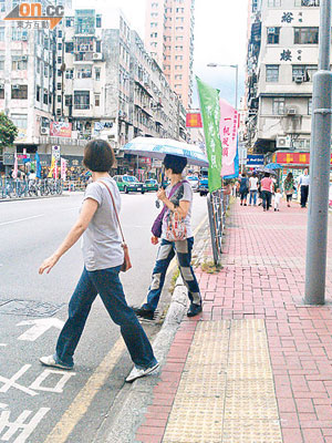 七彩旗幟阻礙行人視線，行人需步出馬路才能留意路面情況，險象環生。