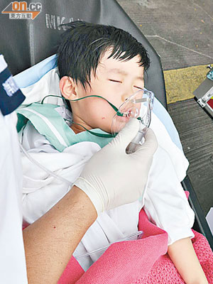 男童戴上氧氣罩送院治療。（郭錦良攝）
