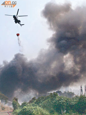 直升機向沙江圍着火的貨倉投擲水彈。（黃君堡攝）