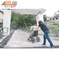 輪椅使用者走上陡峭斜道易生危險，必須有人協助才能前往診所。