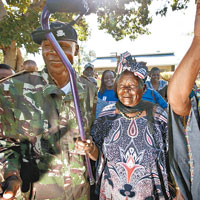 肯尼亞<br>滿臉笑容的薩拉（中）高舉手杖，與鄉親熱烈慶祝奧巴馬連任。