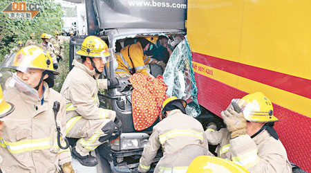 消防員拯救被困駕駛室的跟車工人。（文健雄攝）