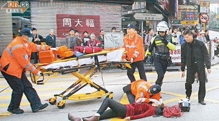 內地女遊客被跑車撞傷，由救護員急救，一名路經鐵騎士（黑衣者）在旁協助。（曾志恒攝）