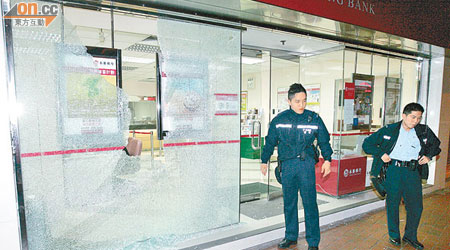 銀行櫥窗玻璃疑遭硬物砸爆，警員到場調查。（周宏杰攝）