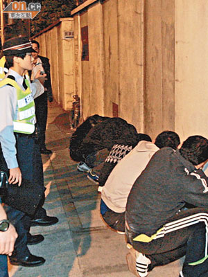 五名涉嫌藏有攻擊性武器男子蹲於路旁接受調查。（呂浩鋒攝）