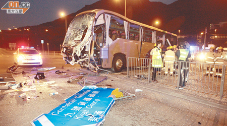 旅遊巴衝上安全島車頭嚴重損毀，一個巨型路牌亦被撞跌。（沈厚錚攝）