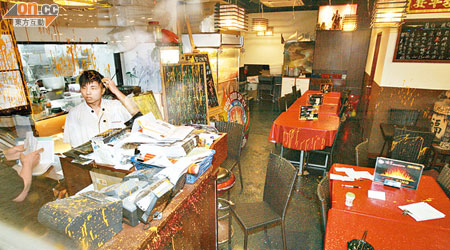 燒烤店內的餐枱及收銀櫃位均被漆油沾污，職員被漆油濺中。