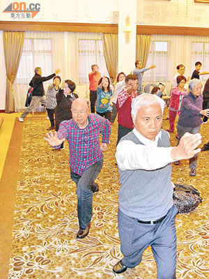 楊釗（最前者）、莊學山（格仔衫）及會員齊學「弓步插掌」，鍛煉腰背腿部肌肉。（受訪者提供）