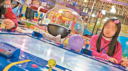 年約五歲女童（右）跟母親（左）在遊戲機中心玩「釣魚機」。