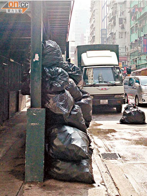 大量滿載汽水罐等雜物的黑色膠袋在行人路上堆積如山，並流出惡臭污水。