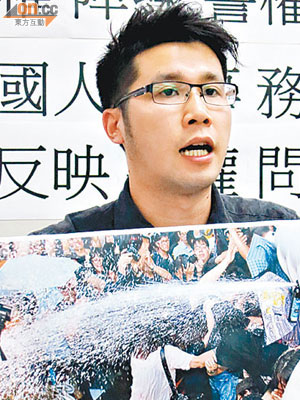 王浩賢展示警方向示威者噴射胡椒噴霧嘅相片。（周依露攝）