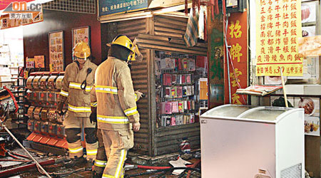 消防員在起火的手機店調查。（吳建明攝）