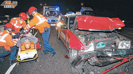救護員在場搶救傷者，肇事的士車頭嚴重撞毀。（沈厚錚攝）
