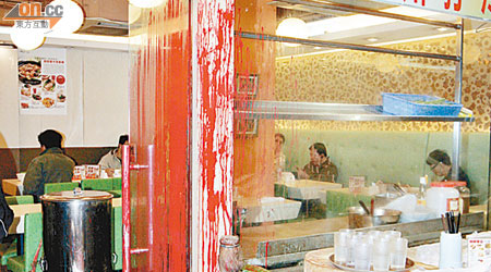 餐廳大門玻璃滿布紅油，旁邊植物及櫥櫃亦遭殃。（沈厚錚攝）