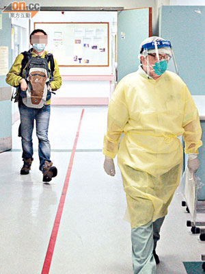 男病人由穿着全副保護衣的醫護人員陪同進入特別用途病房留醫。（馬竟峯攝）