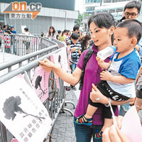 母親及子女把訴求寫上示威單張，並貼在政府總部的欄杆，希望政府落實家庭友善政策。