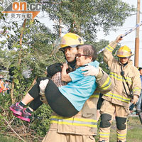 消防員抱起受傷老婦到一邊休息。