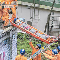 隊員把被困屋頂的傷者放於床架，再以繩索繫穩才搬回地面。