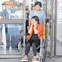 死者妻子掩面痛哭，醫護人員用輪椅將她推往休息。
