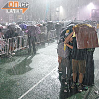 晚會全程都下着大雨，部分無帶雨具的參加者惟有用紙皮擋雨。（蘇文傑攝）