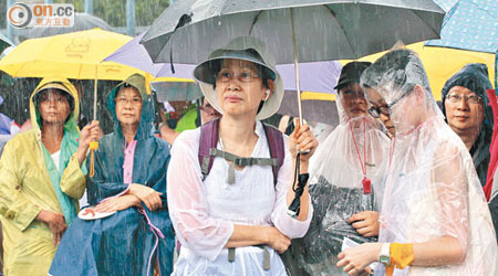 遊行人士等候出發時，無私分享雨衣和雨傘。（蘇文傑攝）