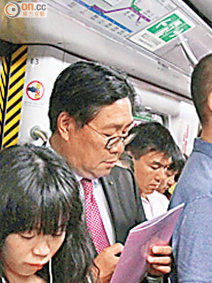車廂逼滿乘客，馬時亨（左二）冇位坐亦不忘低頭篤電子產品。