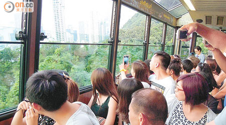 遊客坐山頂纜車時總愛望窗外的維港景，不時發現高樓大廈像傾斜了。（李盛芝攝）