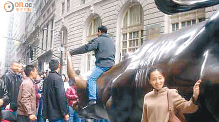 缺德中國遊客爬上美國華爾街的銅牛雕塑拍照。（資料圖片）