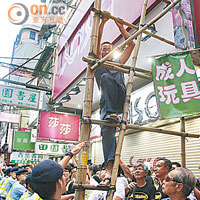 有旁觀市民為求拍攝照片，冒險爬上竹棚時遭警員勸喻。