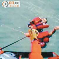 政府飛行服務隊人員將怒海中救生筏上的船員，逐一救上直升機。