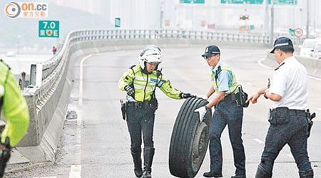 兩名警員合力將甩脫的車轆推返肇事泥頭車。（馬竟峯攝）