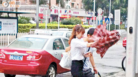 「天兔」襲廣東省，市民外出時雨傘被強風吹歪，狀甚狼狽。（張琦攝）