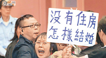 張女士高舉「沒有住房、怎樣結婚」的紙牌，聲淚俱下要求政府解決房屋問題。（陸智豪攝）