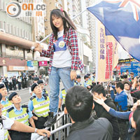 有少女示威者手持港英旗，站在鐵馬上與警對峙。（陸智豪攝）